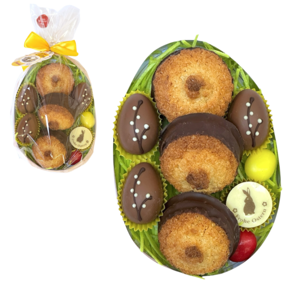 Ovales Osterpräsent mit Kokoskuppeln, Pralinen, Ostergras und bunter Schleife